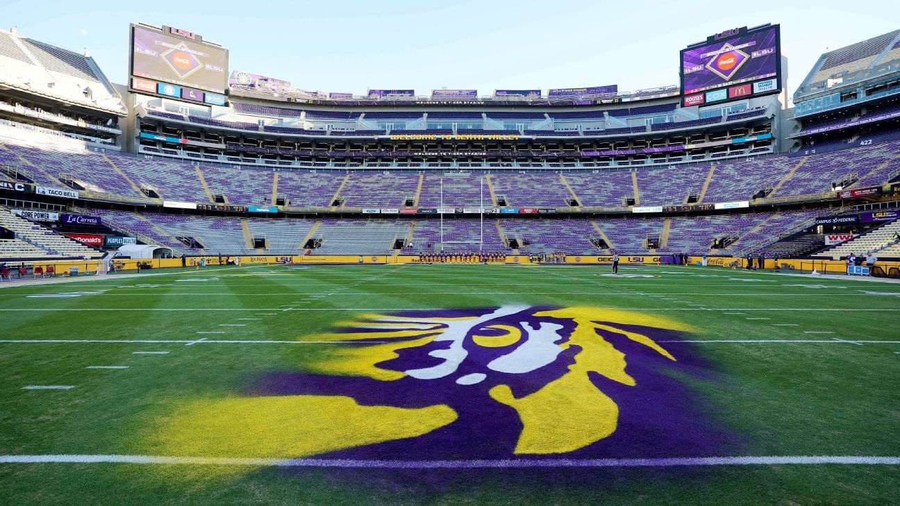 Empty football stadium with purple and yellow seats and a large tiger logo on the field.
