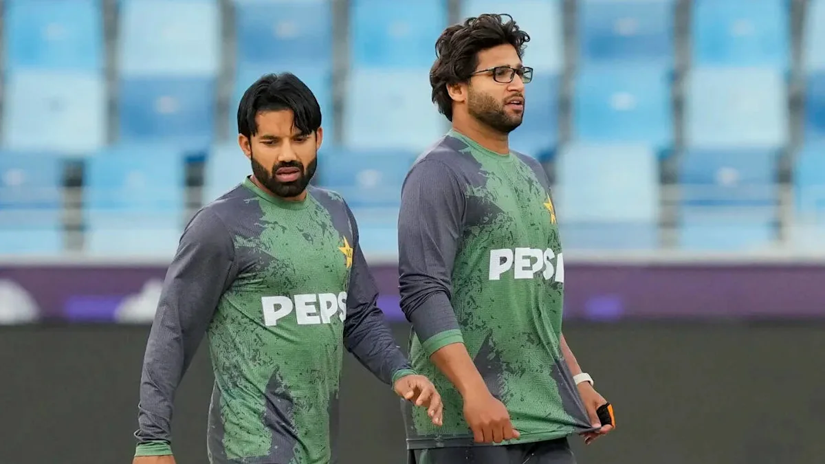 Two Pakistan cricket players in green Pepsi jerseys walking together on a cricket field