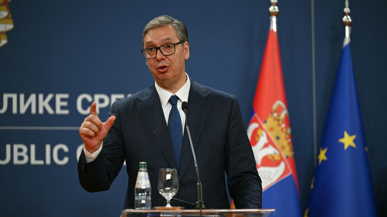 Man in suit speaking at a podium with Serbian and European Union flags behind him