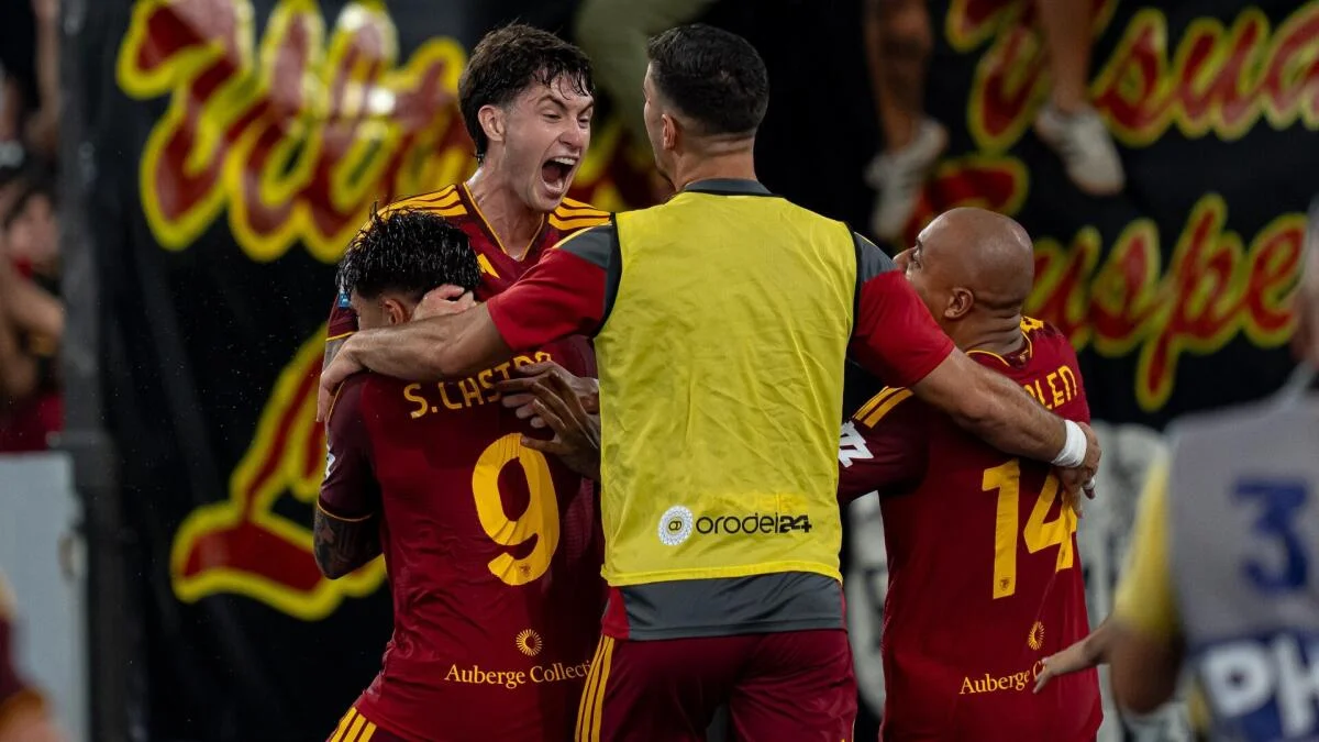 AS Roma players and a substitute in a yellow bib celebrate together during a match