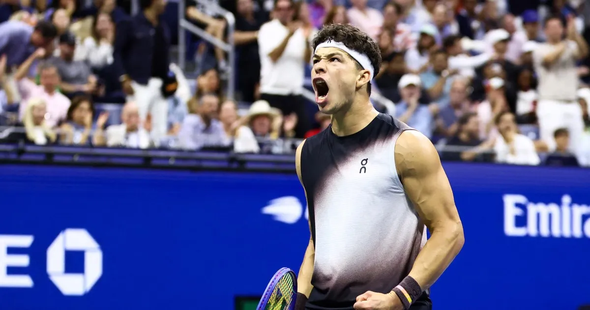 Tennis player in black-and-white shirt shouting and celebrating on court before a cheering crowd