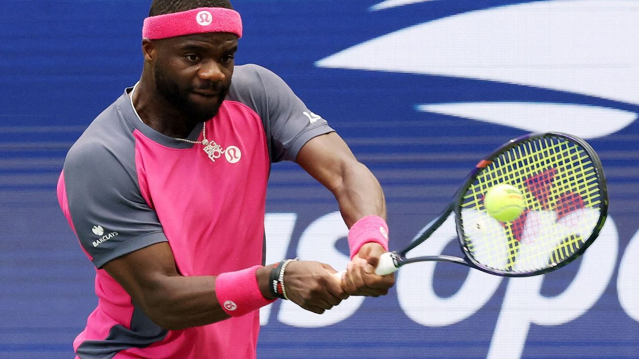 Tennis player in pink and gray athletic wear returns a ball during a match.