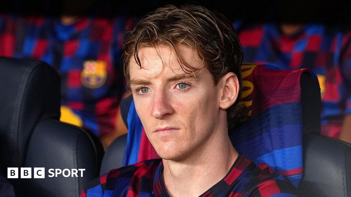 Footballer seated on a Barcelona bench wearing a blue-and-red club shirt