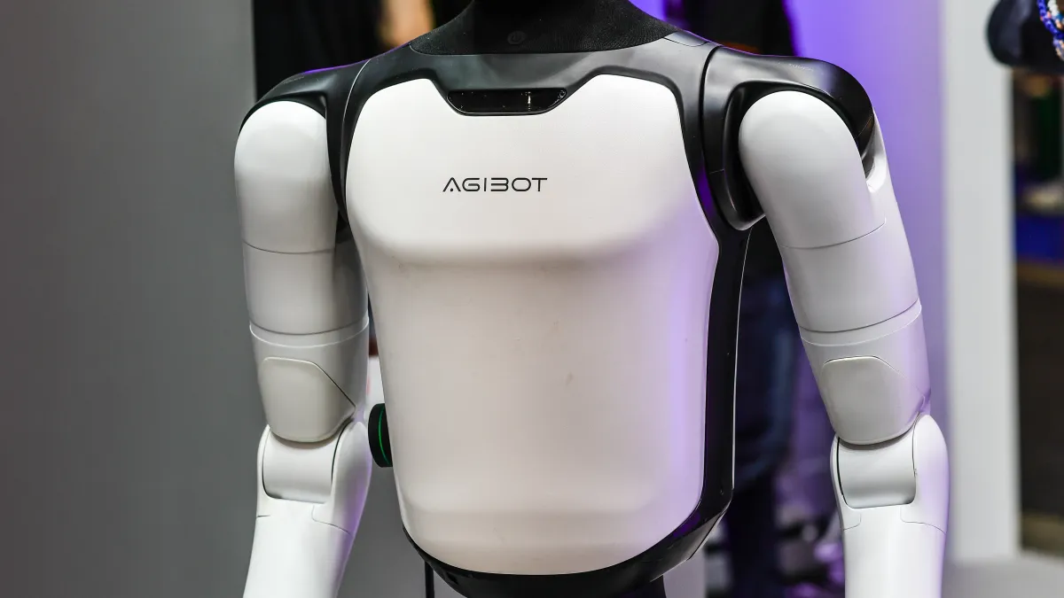 Close-up of a white and black humanoid robot torso with articulated arms and AGIBOT branding.