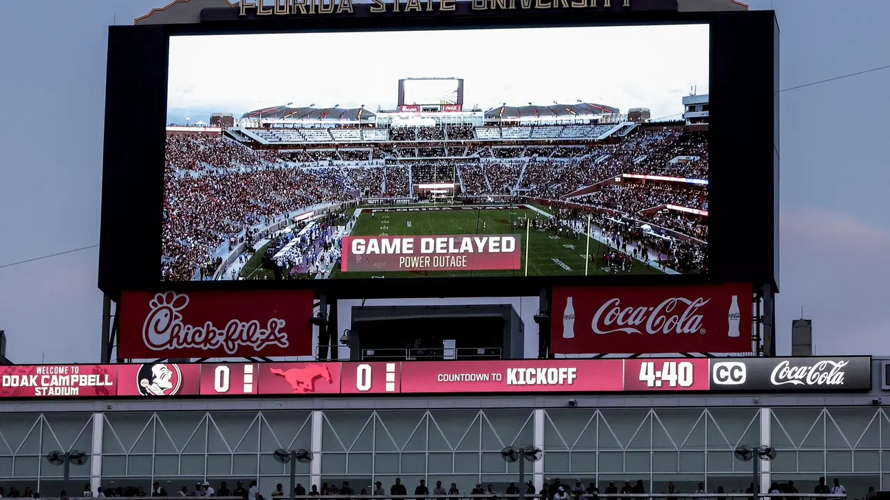Stadium scoreboard displays a game delay due to a power outage during a football game.