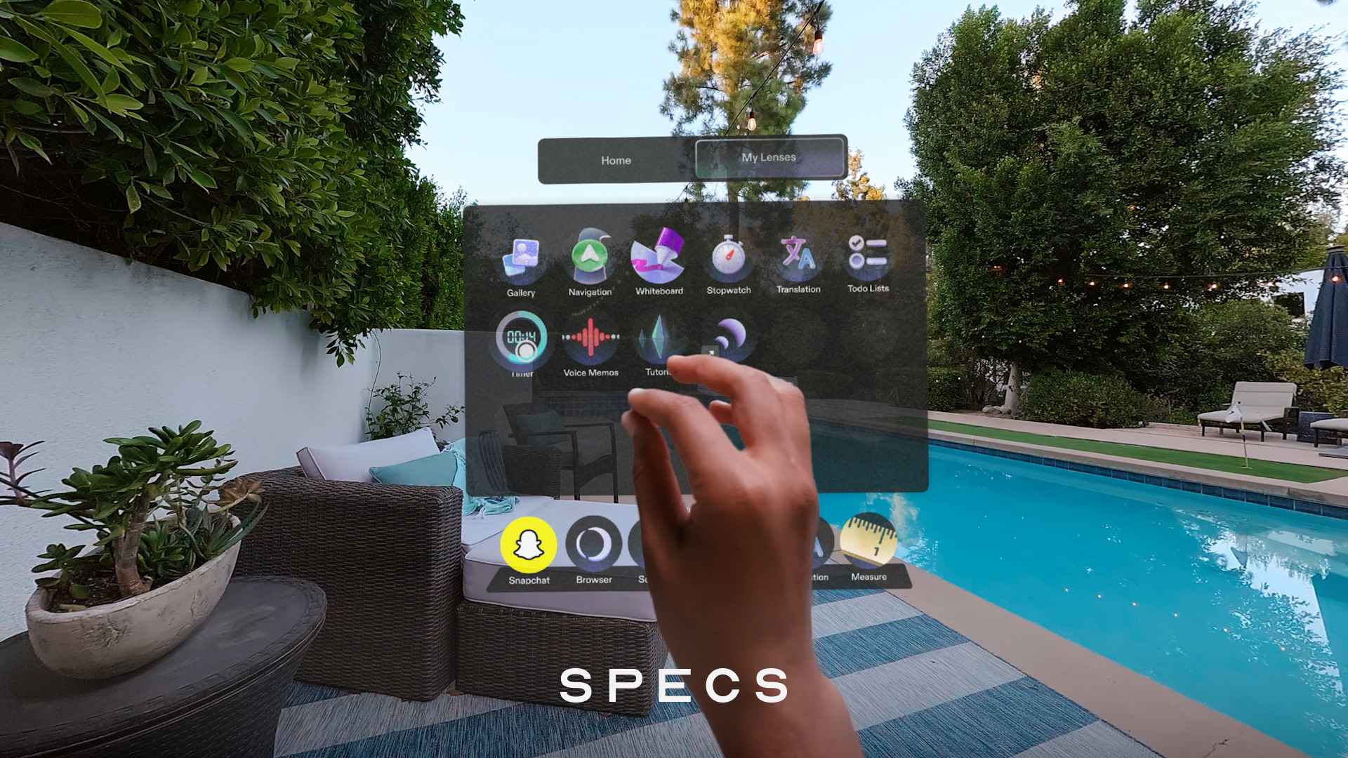 Person interacts with a transparent smart-glasses interface displaying apps beside a swimming pool.