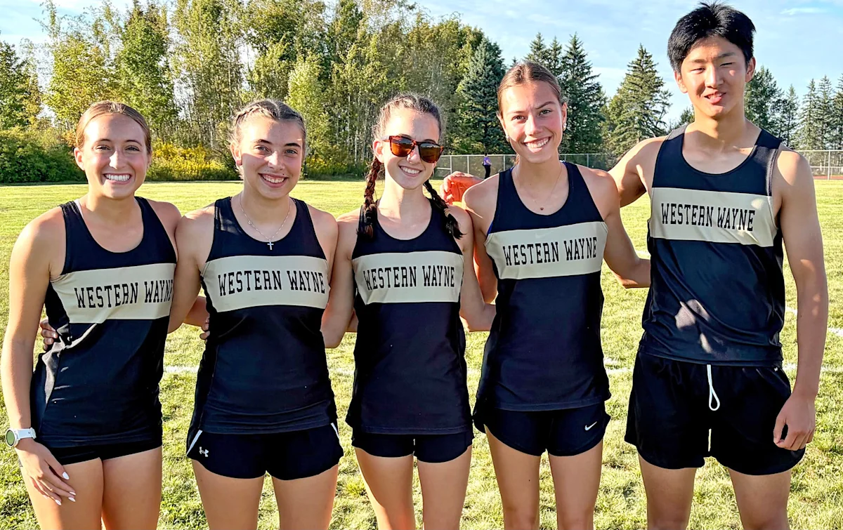 Five Western Wayne cross country runners pose together on a sunny grassy field.