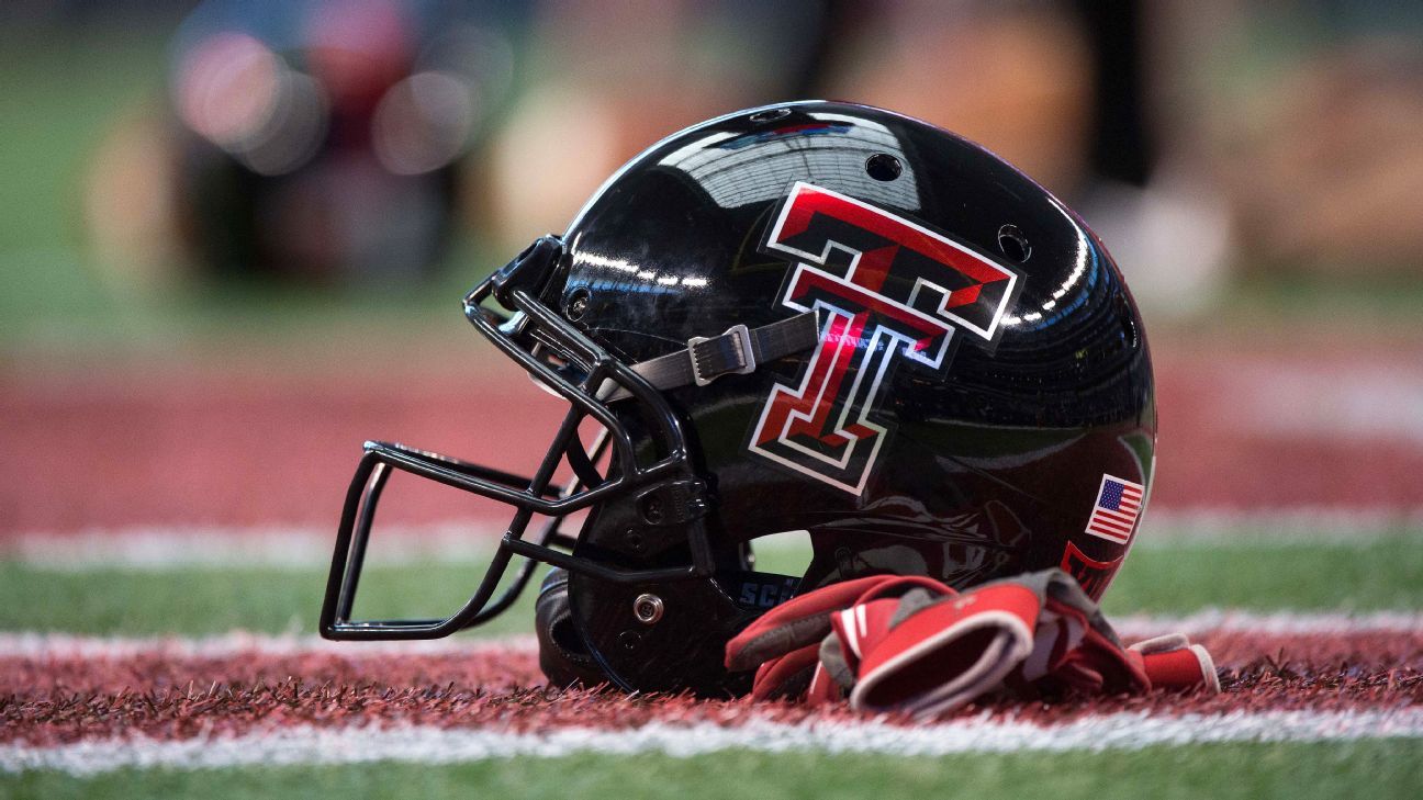 Black Texas Tech football helmet and red gloves resting on a marked football field