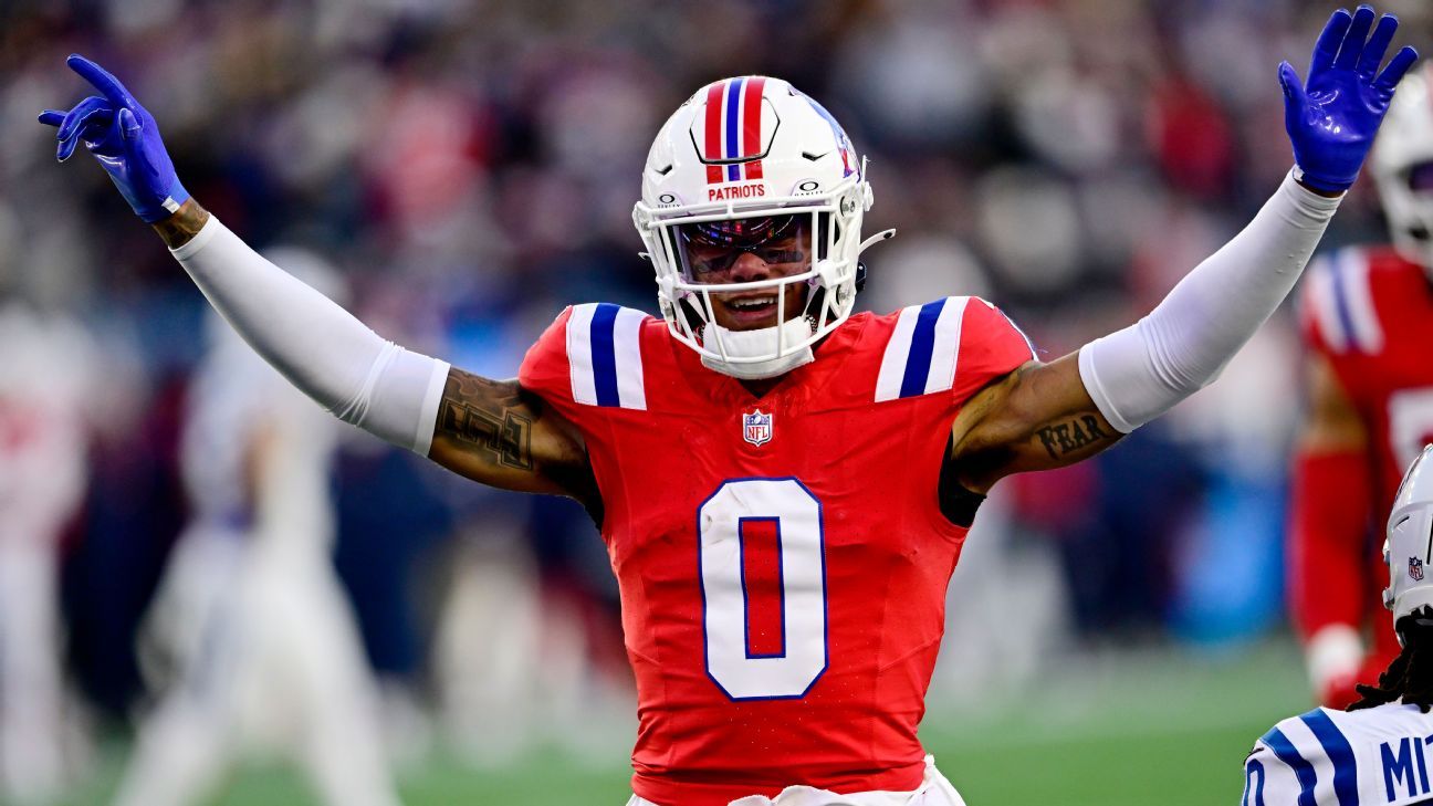 New England Patriots player in red uniform raises both arms during a football game