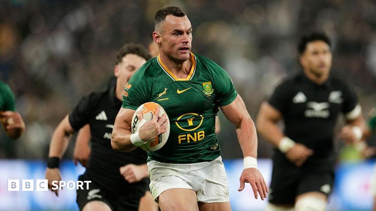 South African rugby player carrying the ball while running past opposing players