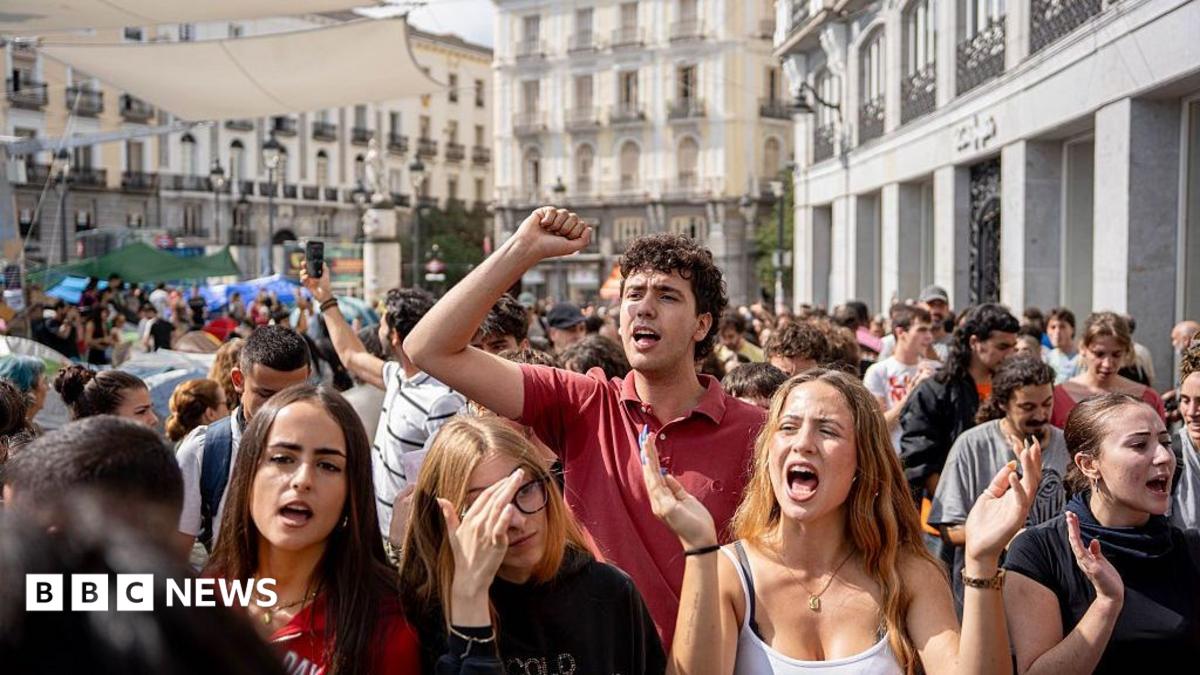 A man raises his fist as women and others gather in a crowded city street.
