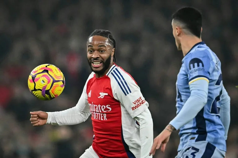 Footballer in red and white Arsenal kit watches a yellow ball during a match