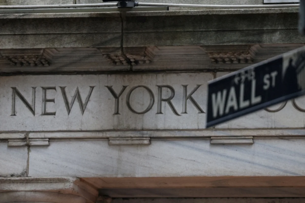 Wall Street street sign in foreground against carved New York building facade