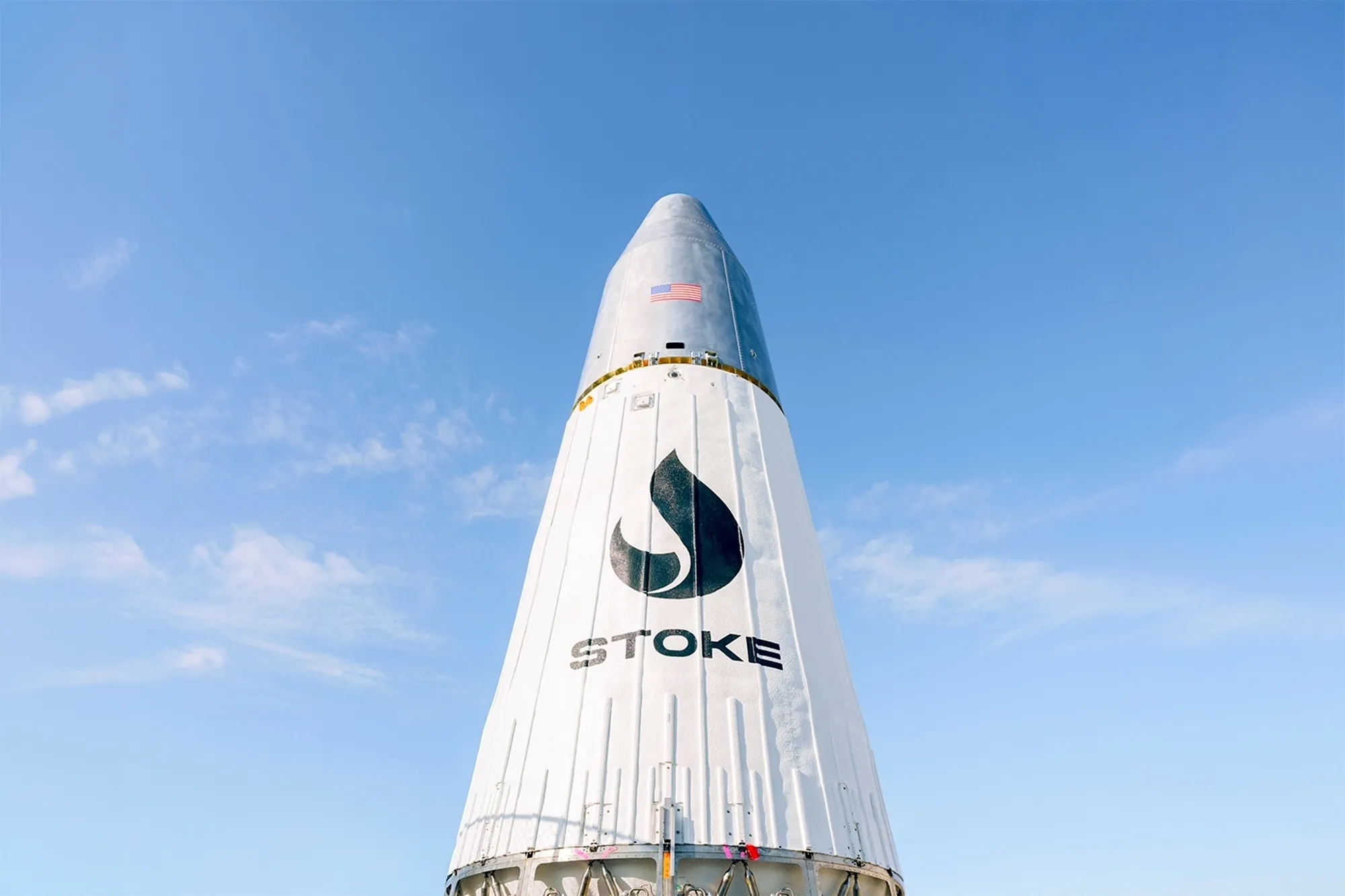 White Stoke Space rocket nose cone against a bright blue sky with scattered clouds
