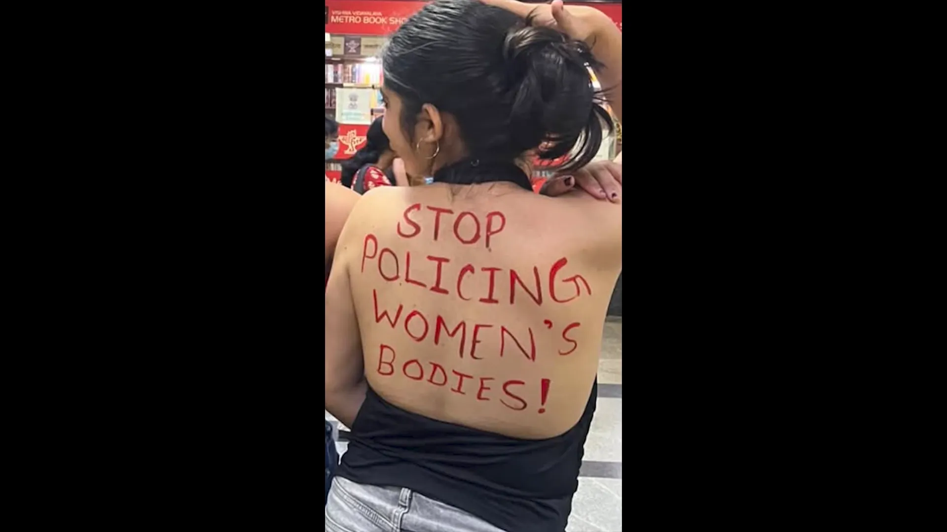A woman with red lettering on her back reading “Stop policing women’s bodies!”