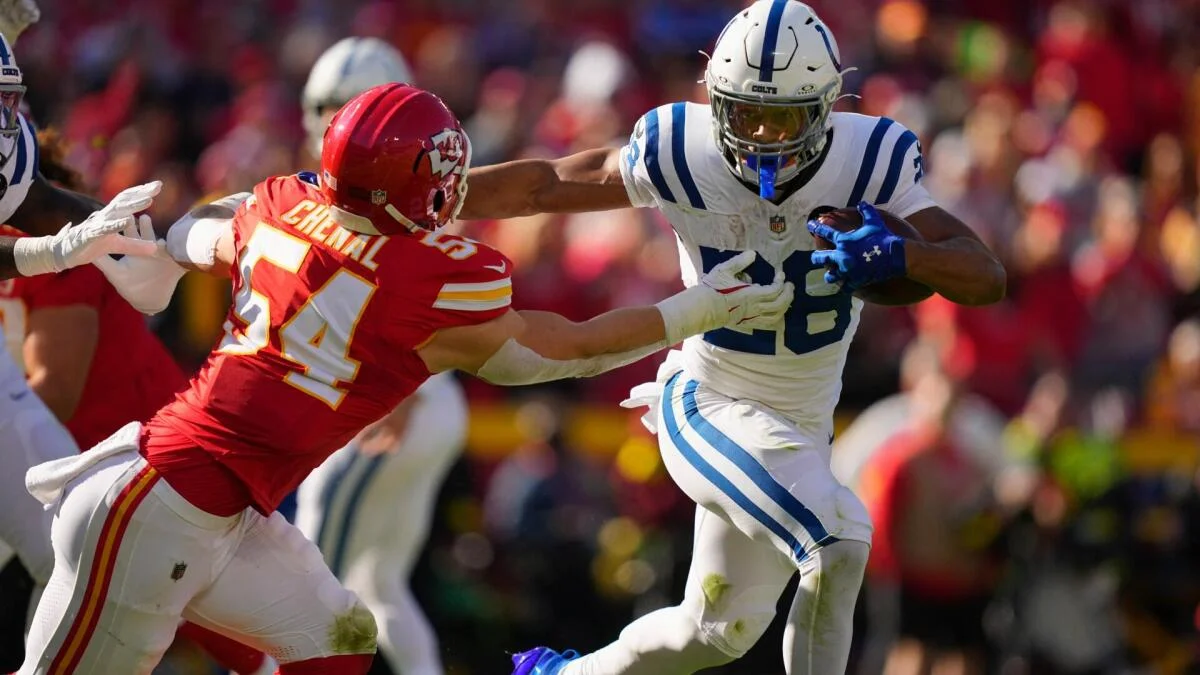 Colts ball carrier runs past a Chiefs defender reaching to make a tackle.