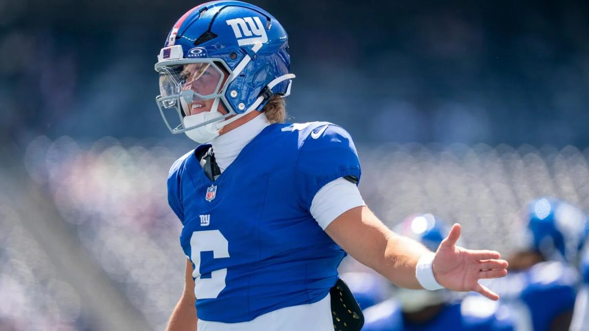 New York Giants football player wearing helmet and blue uniform gestures on the field.