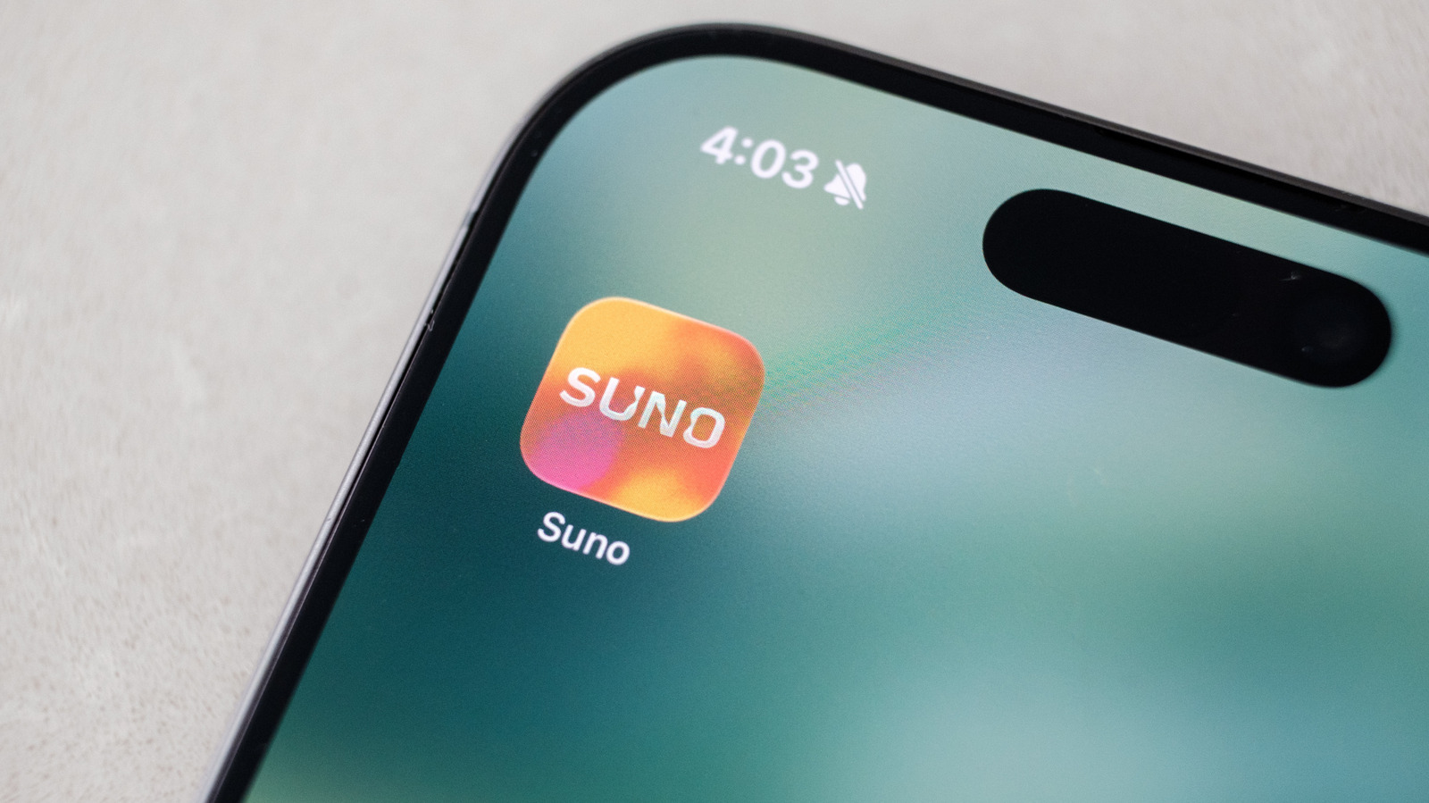Close-up of a smartphone displaying the colorful Suno app icon and name.
