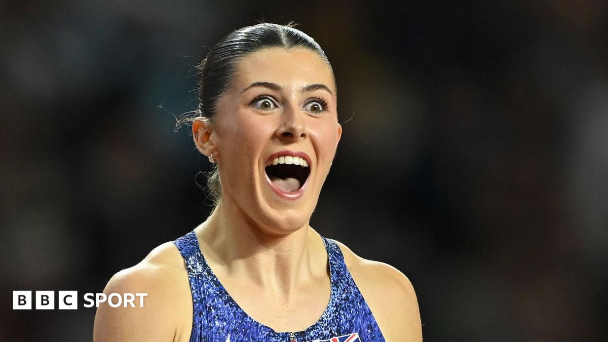 Female athlete with tied-back hair celebrates energetically while wearing a blue sports vest.