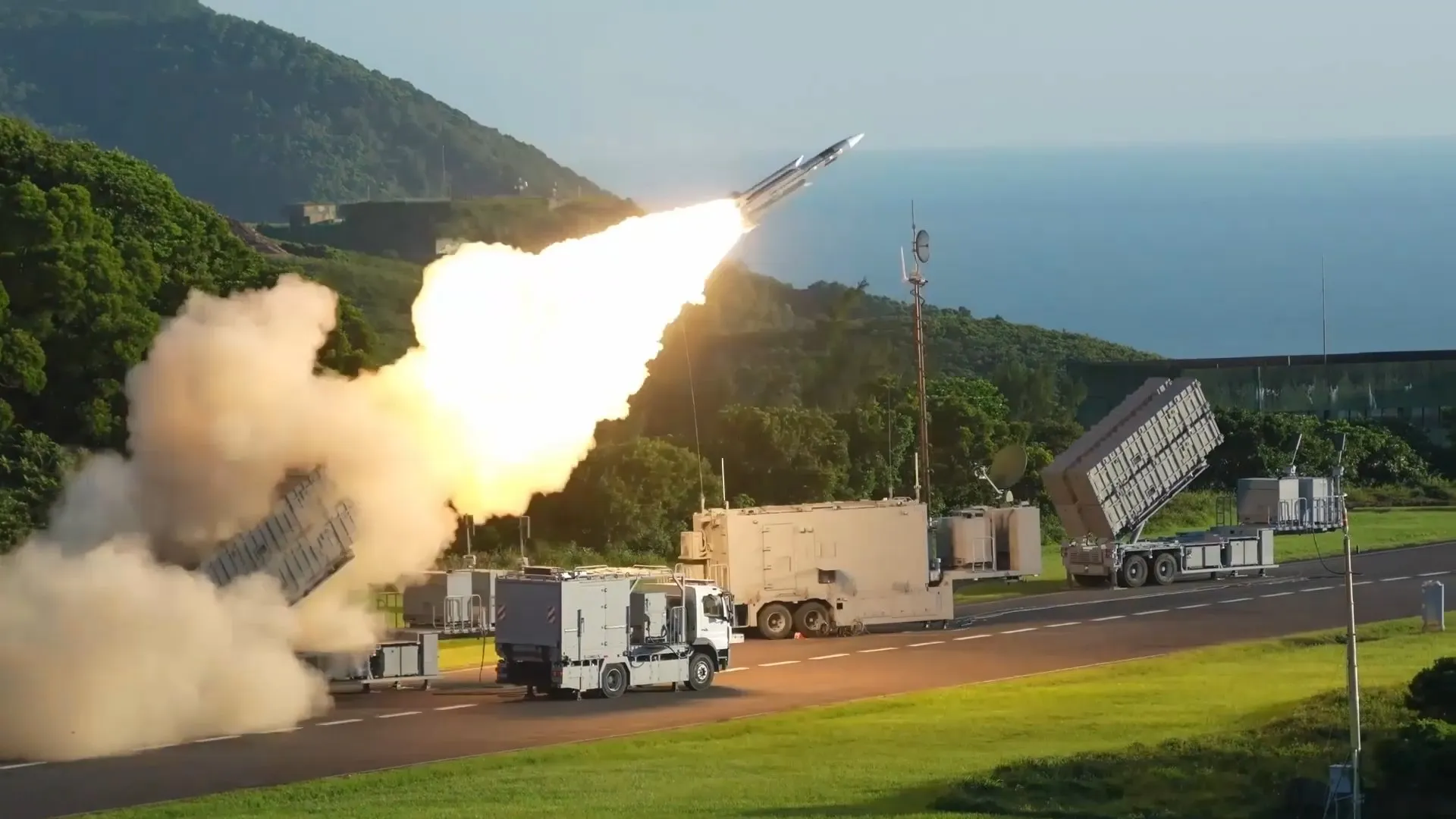 Missile launches from a mobile coastal defense system near trucks and radar equipment.
