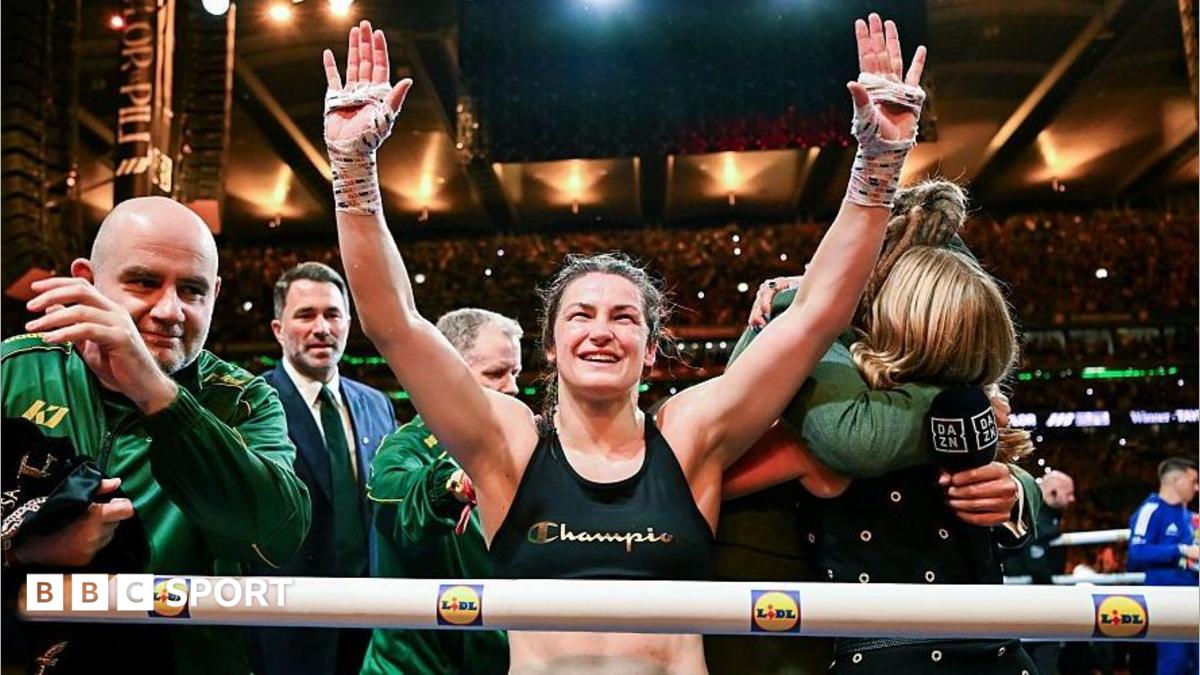 Victorious female boxer raises both taped hands in the ring as supporters celebrate around her