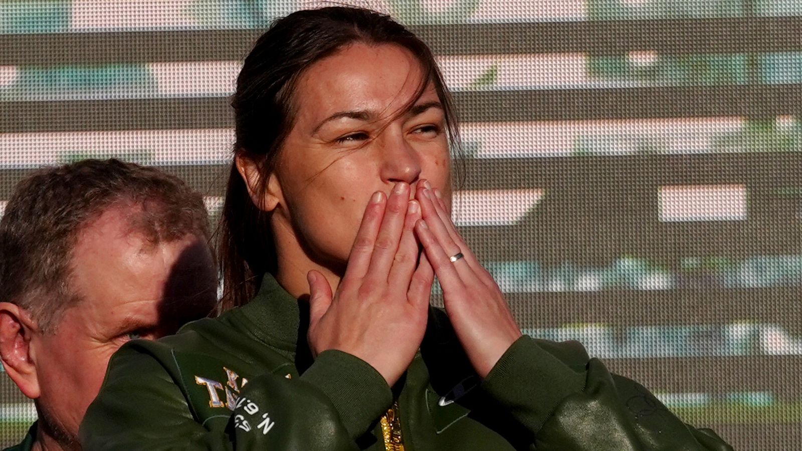 Female fighter covers her mouth with both hands while standing beside a man backstage.