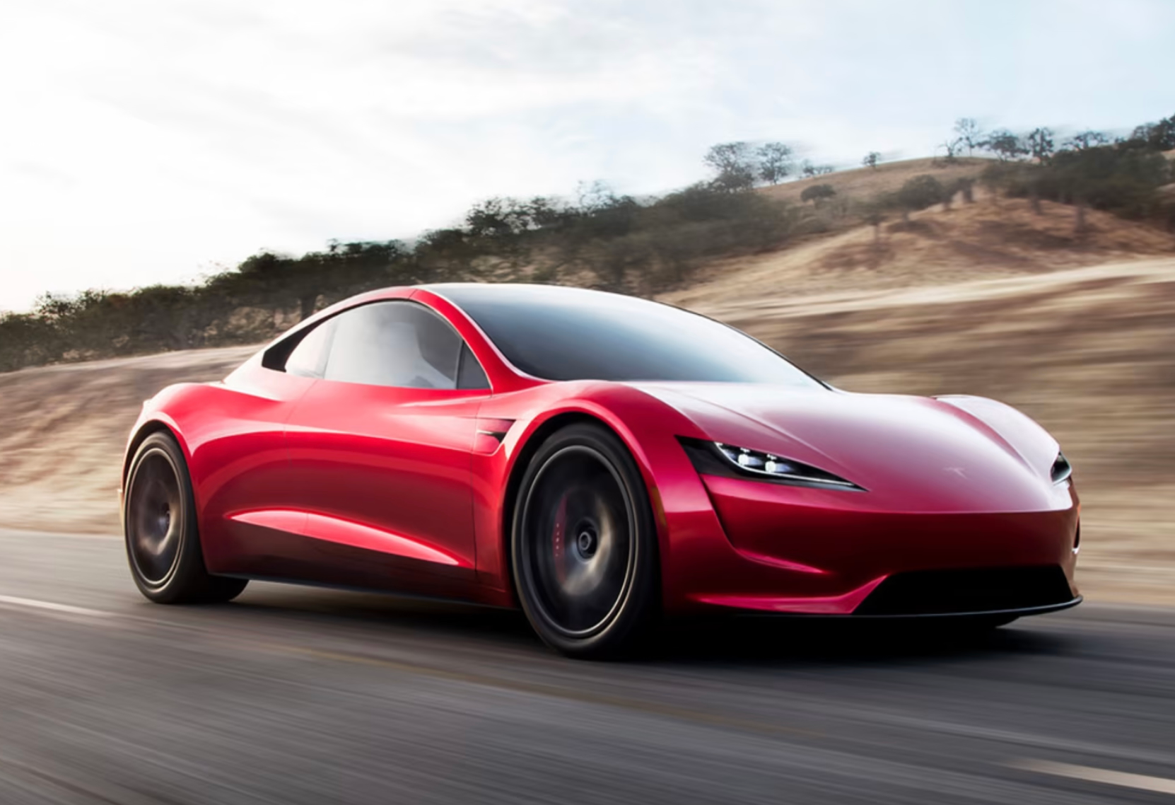 Red sports car driving on a road through a dry, hilly landscape