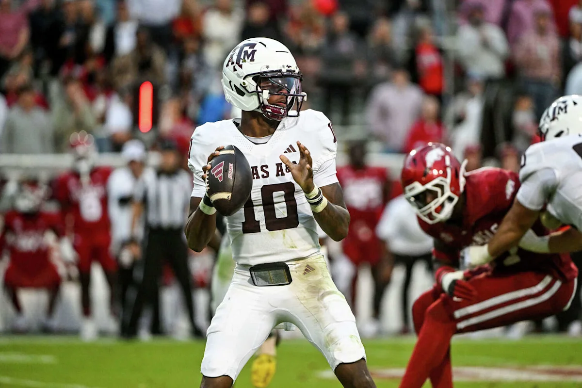 Texas A&M quarterback in white uniform prepares to pass during a football game.