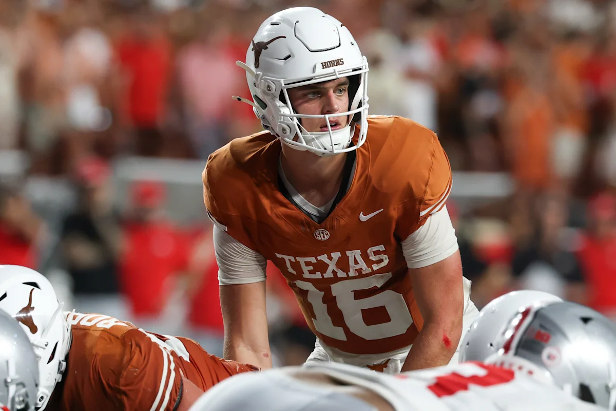 Football player in a Texas Longhorns uniform crouches behind the line of scrimmage.