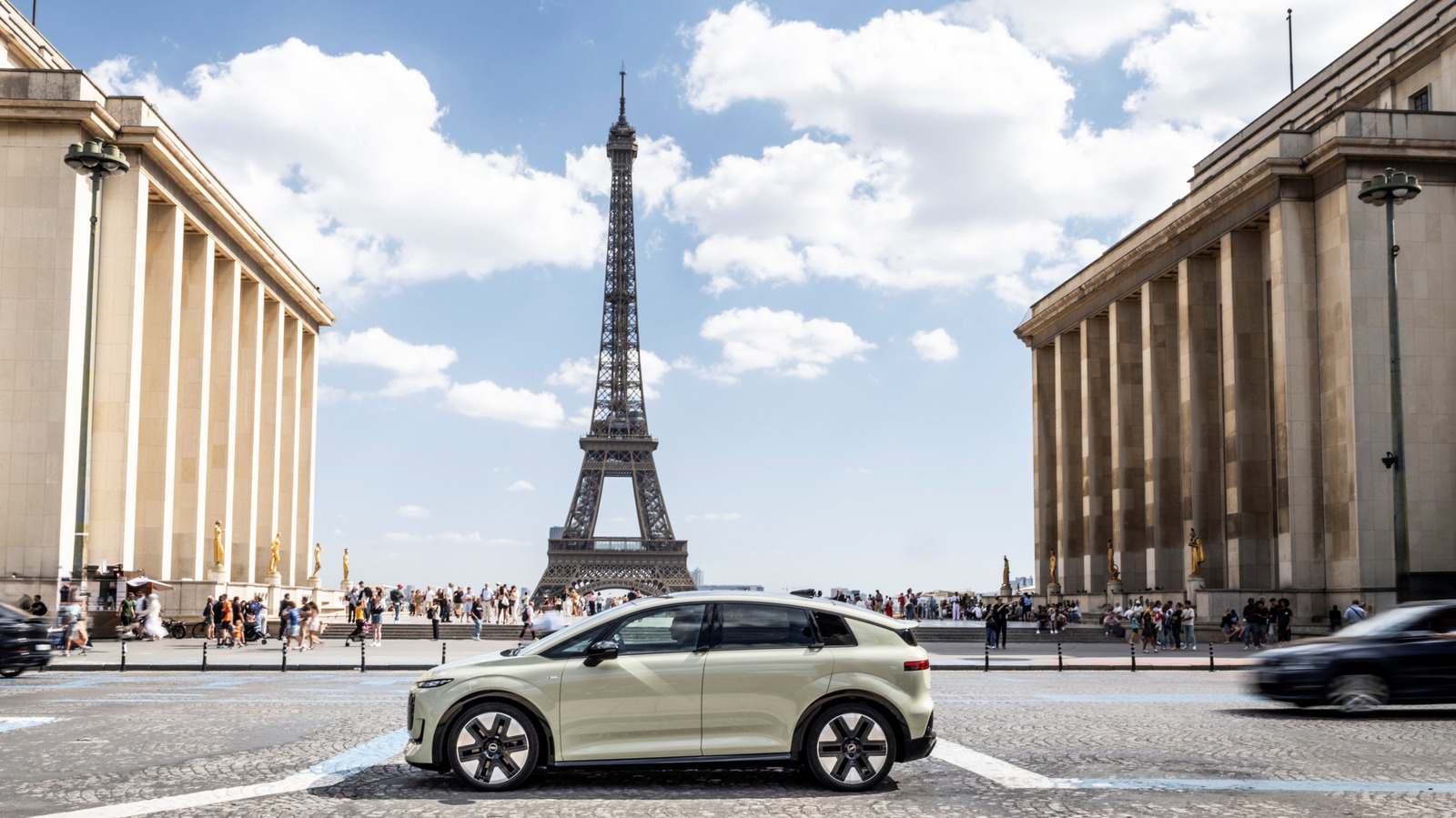 Light-colored Audi electric vehicle parked in front of the Eiffel Tower between grand colonnaded buildings