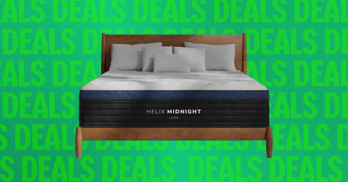 A bed with white bedding and a black Helix Midnight Luxe mattress on a wooden frame.