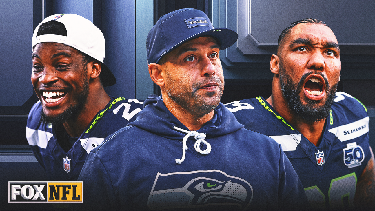 Three men in Seattle Seahawks apparel pose against a dark paneled background.