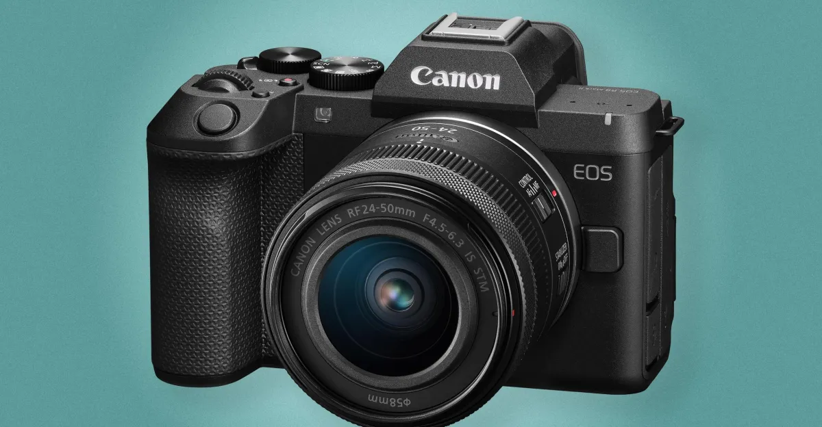 Black Canon mirrorless camera with attached zoom lens against a turquoise background