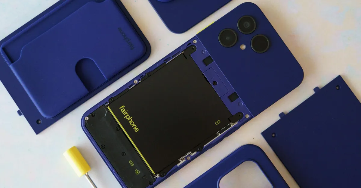 Disassembled blue Fairphone showing its battery, camera module, covers, and yellow screwdriver