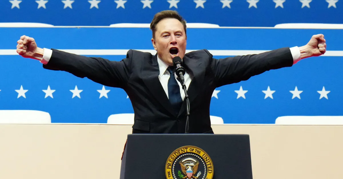 Elon Musk stands at a podium with arms outstretched before a blue star-patterned backdrop.