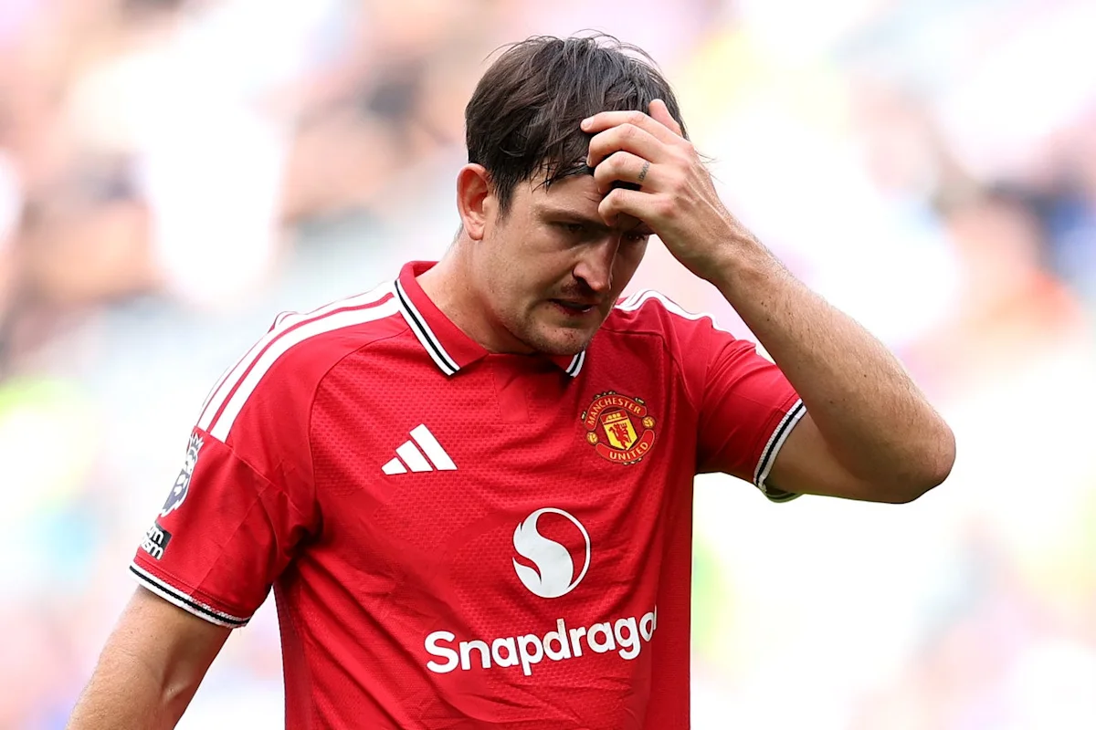 Footballer in a red Manchester United jersey holds his head during a match.