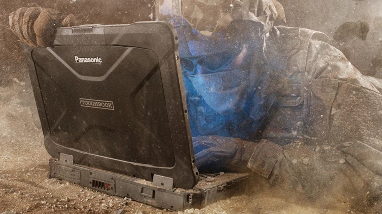 Rugged Panasonic Toughbook laptop lying beside a dust-covered person in protective clothing