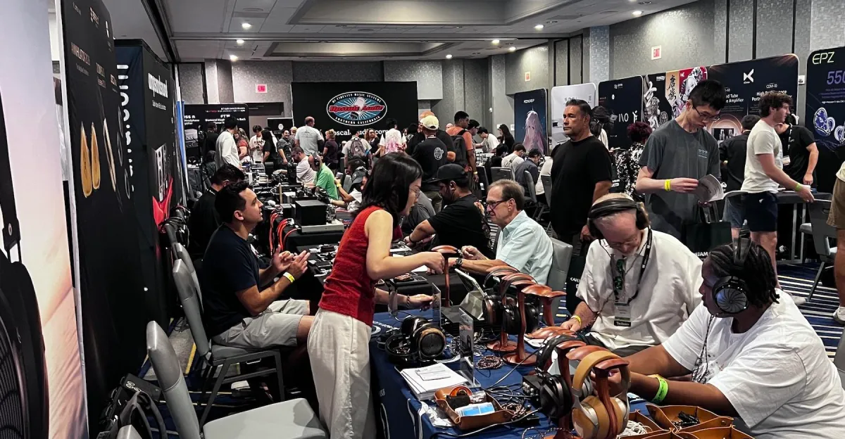 Attendees browse and test an array of headphones at a busy audio equipment exhibition.