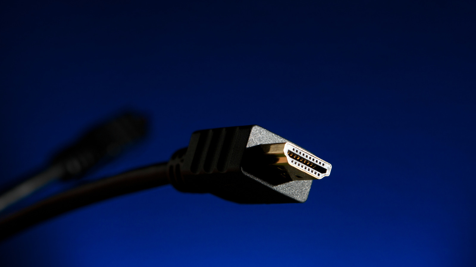 Close-up of an HDMI cable connector against a dark blue background