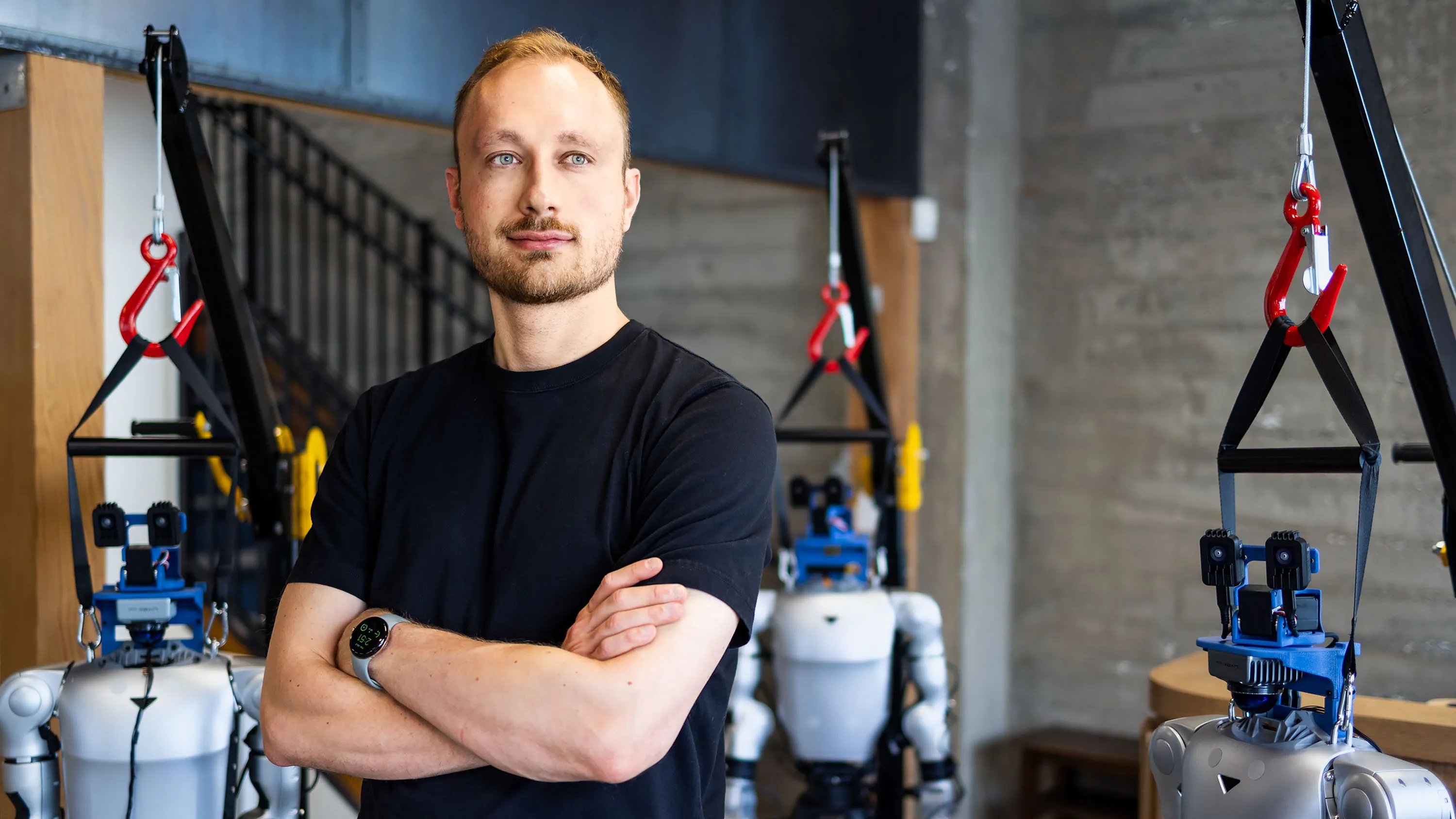 Man with folded arms standing among robotic systems in a laboratory