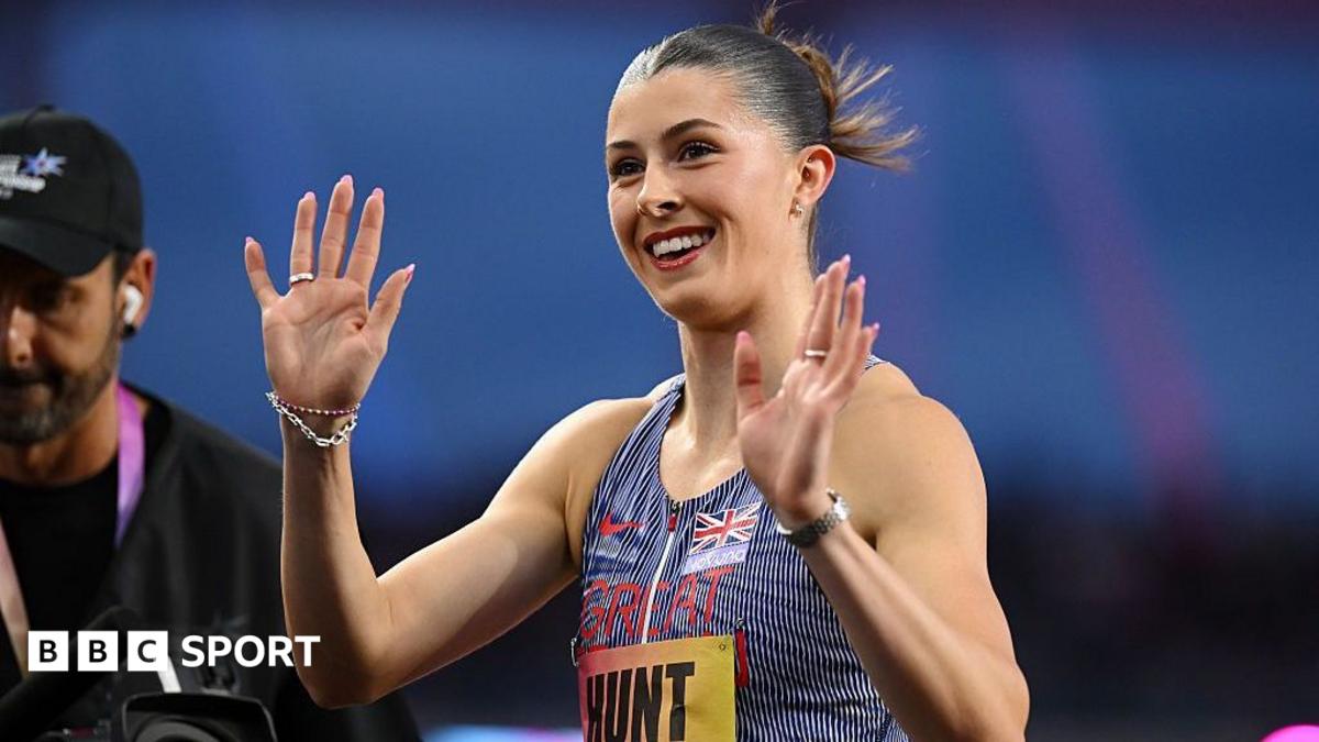 Smiling female athlete in a Great Britain vest waves both hands during a sporting event.