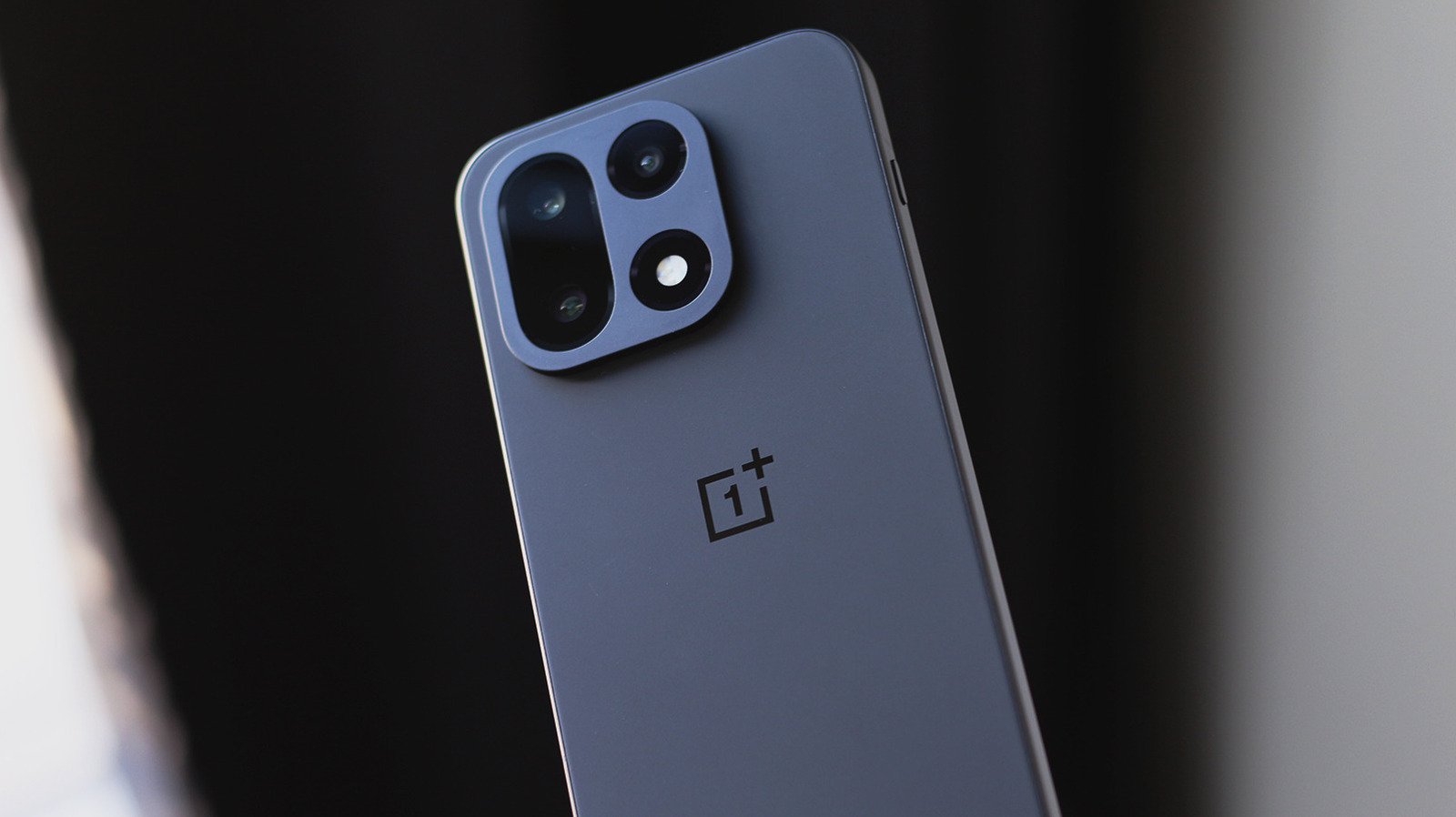 Close-up of the back of a dark blue OnePlus smartphone, showing its camera module and logo.