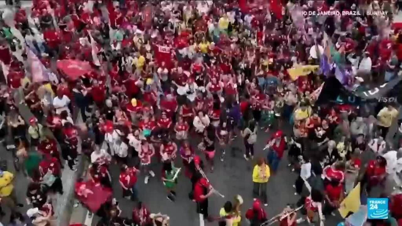 Large crowd in red clothing waving flags and gathering along a city street