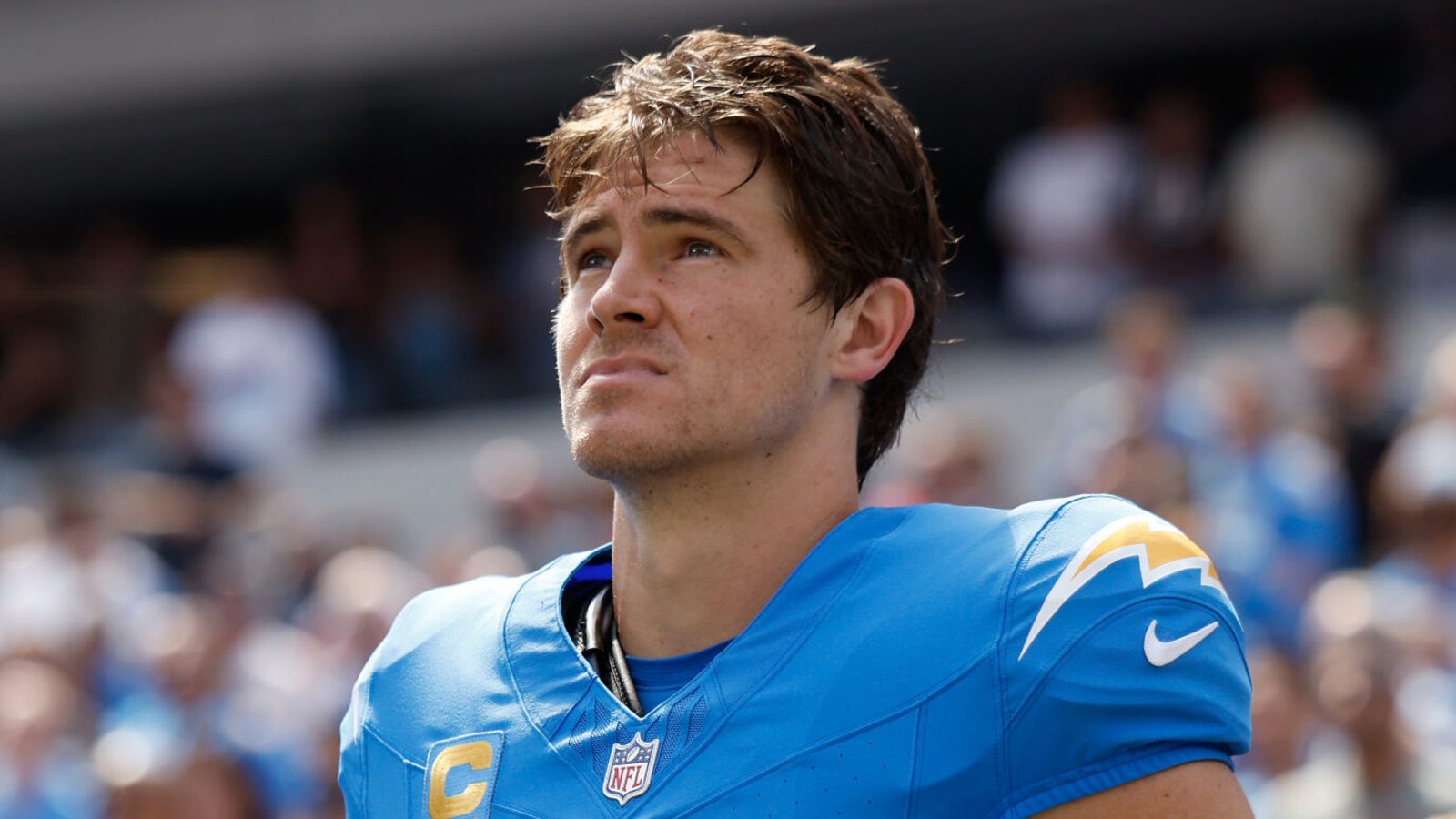 Football player in blue jersey looking upward during a game