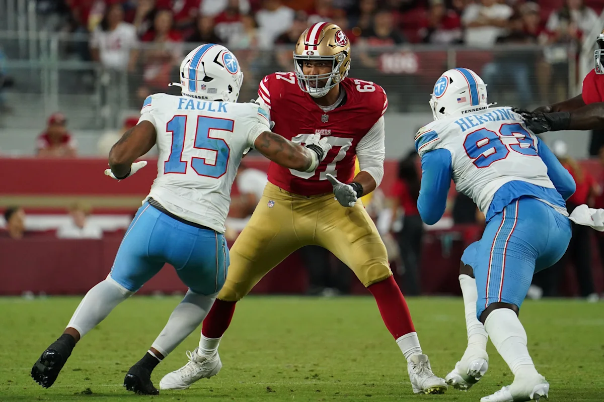 Two Tennessee Titans players block a San Francisco 49ers player during a football game.