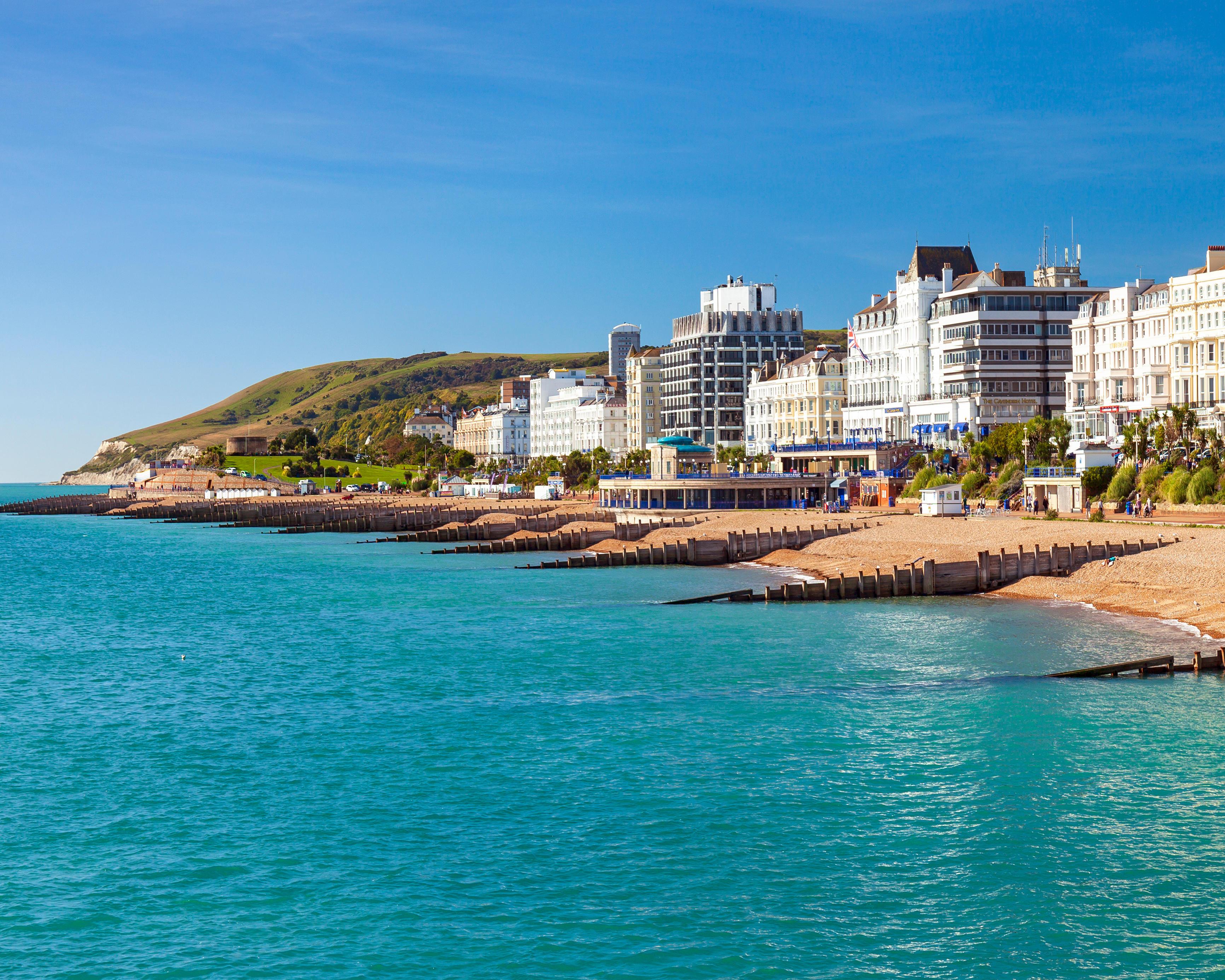 Seaside resort with turquoise water, pebble beaches, promenade, hillside and rows of hotels under blue sky