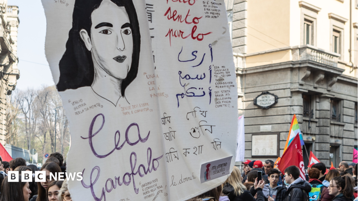 Protesters gather behind a large illustrated banner featuring a woman and handwritten messages.