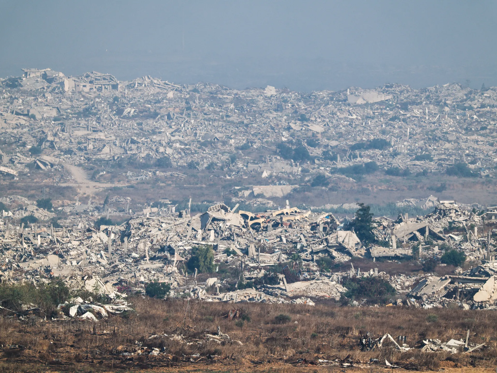 Wide view of extensive urban destruction, with collapsed buildings and rubble stretching across the landscape.