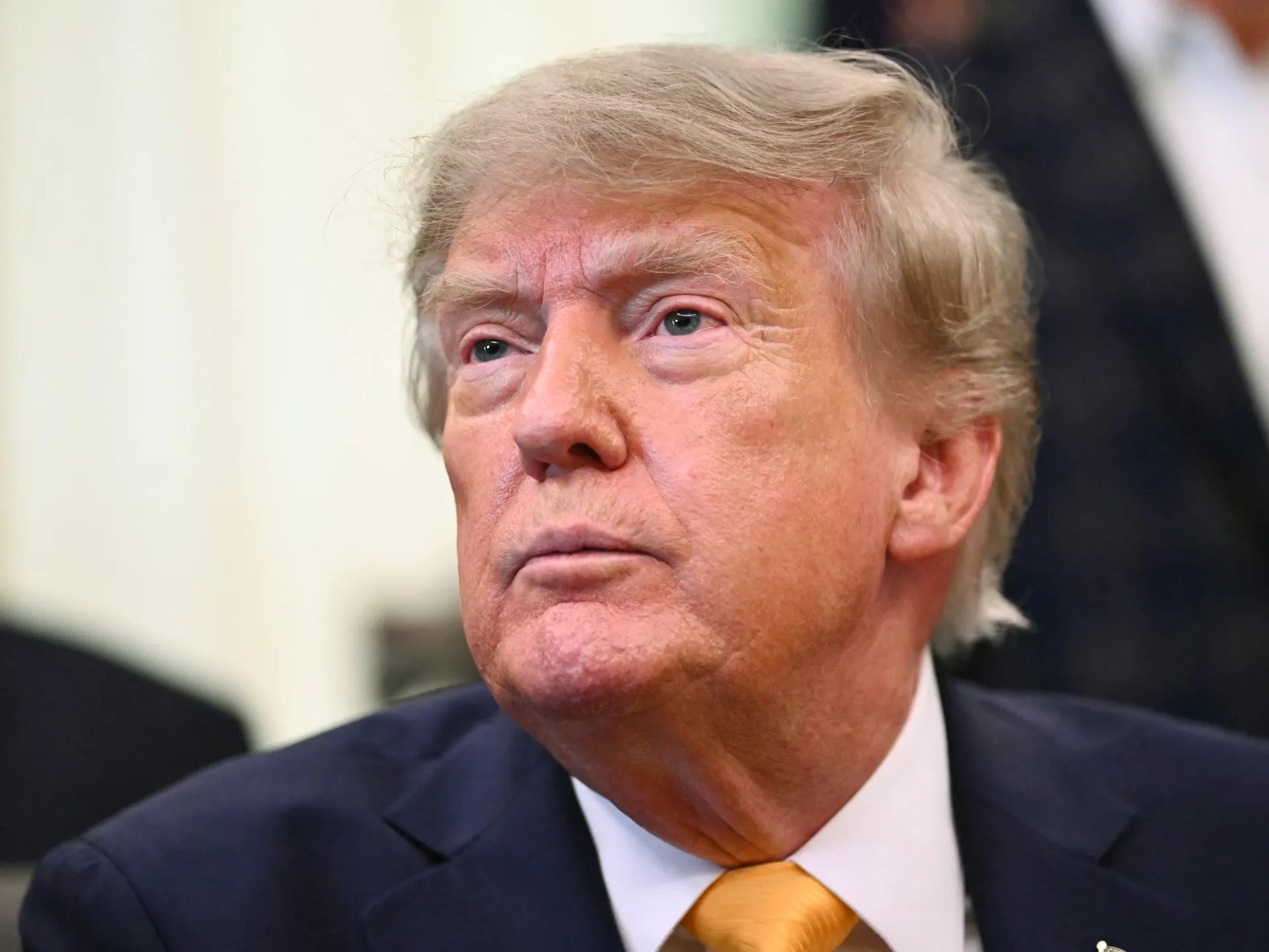 Close-up portrait of Donald Trump wearing a dark suit and gold tie