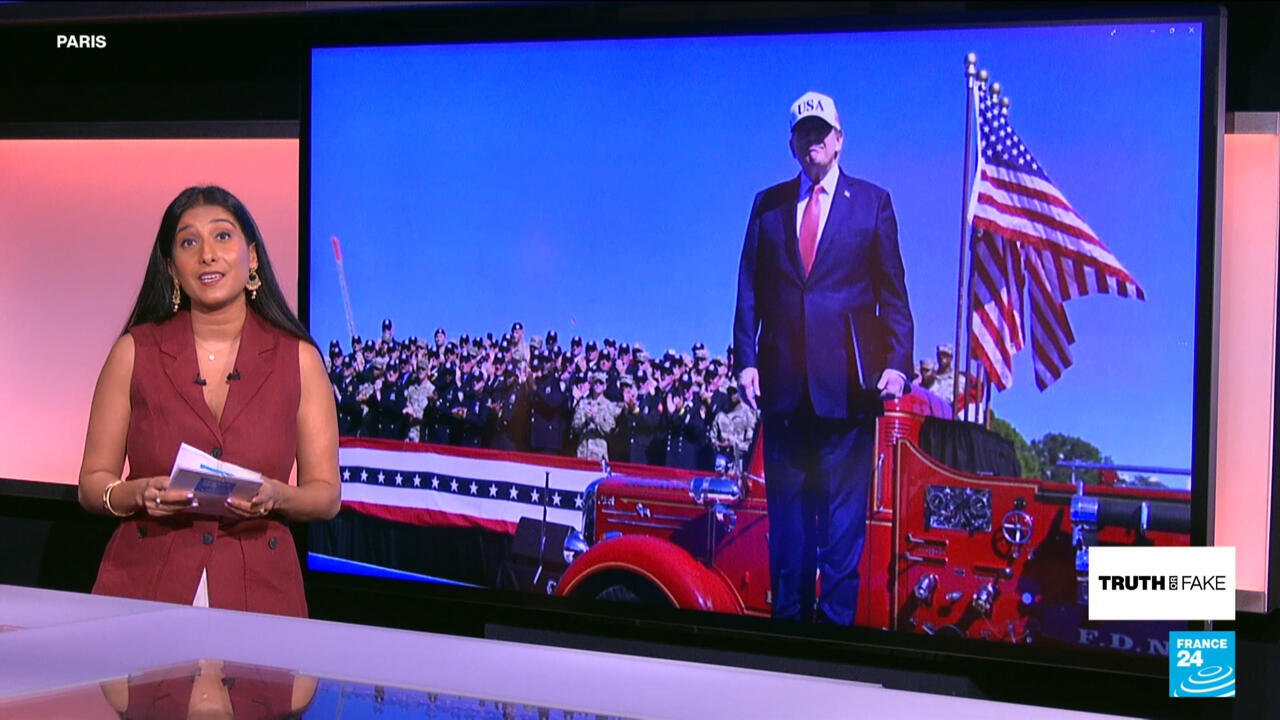 News presenter stands beside screen showing a suited man near a fire truck and American flag.